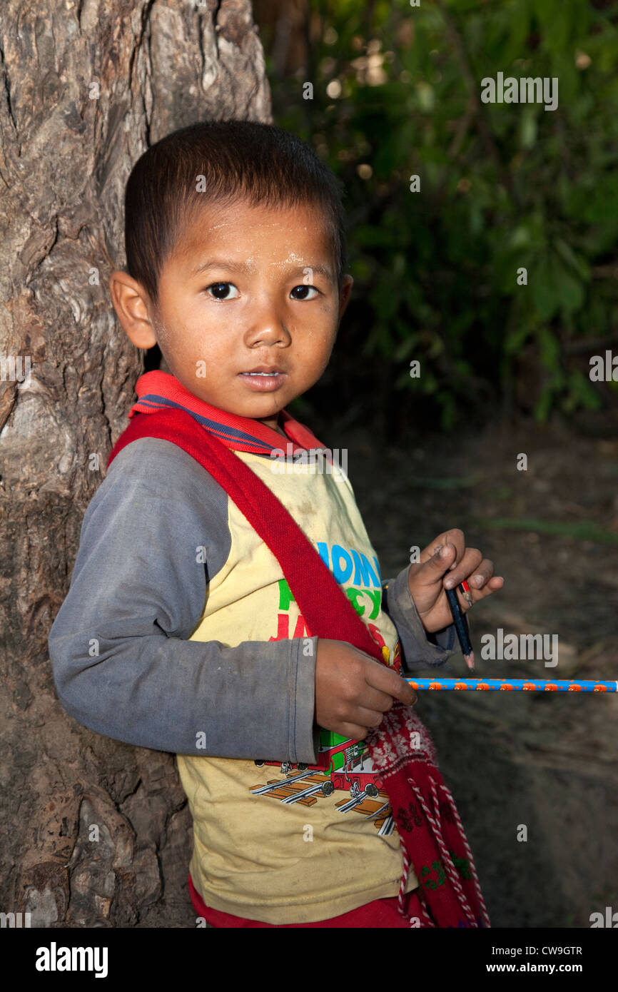 Le Myanmar, Birmanie. Jeune garçon birman dans Village près de Bagan holding nouveau crayon et deux anciens. Banque D'Images