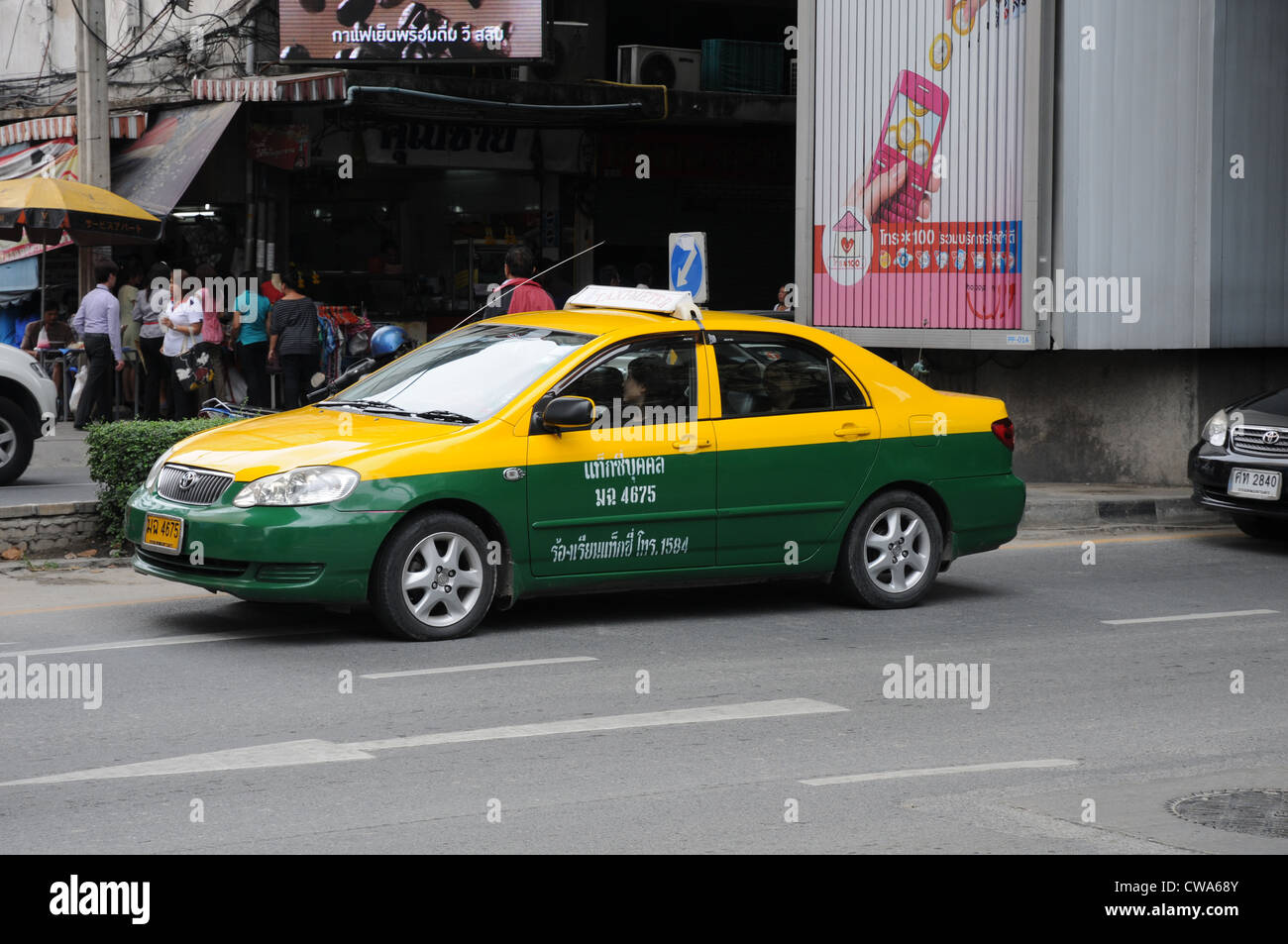 Conduite de taxi jaune et vert le long de la Sukhumvit Road, Bangkok occupé. Banque D'Images