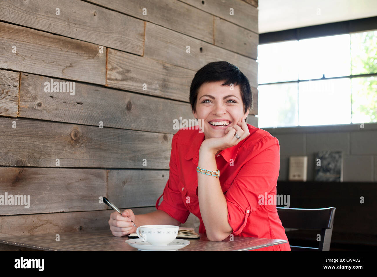 Woman wearing red shirt assis dans un café, portrait Banque D'Images