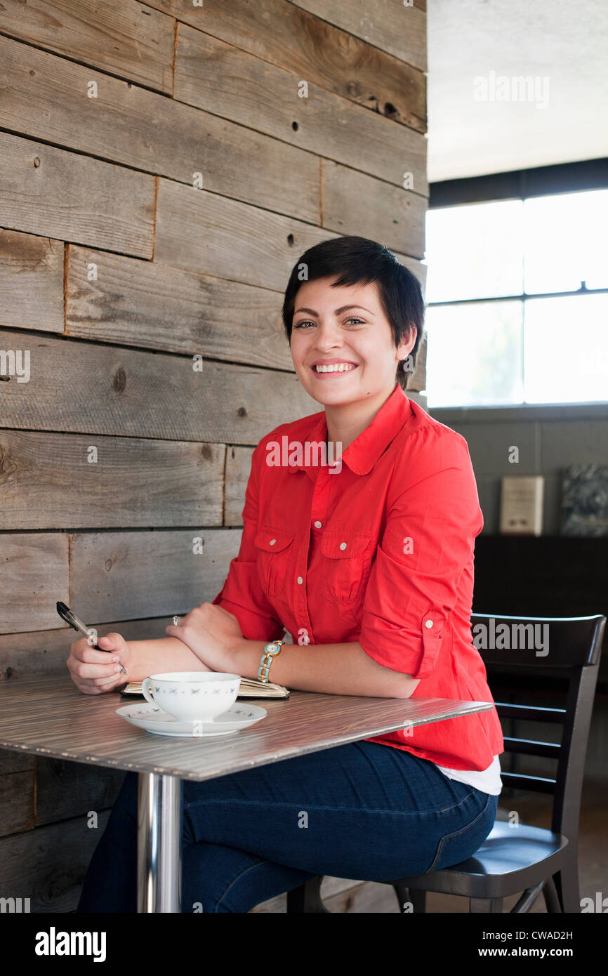 Woman wearing red shirt assis dans un café, portrait Banque D'Images