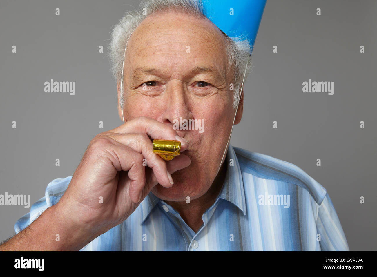 Senior man with party blower, portrait Banque D'Images