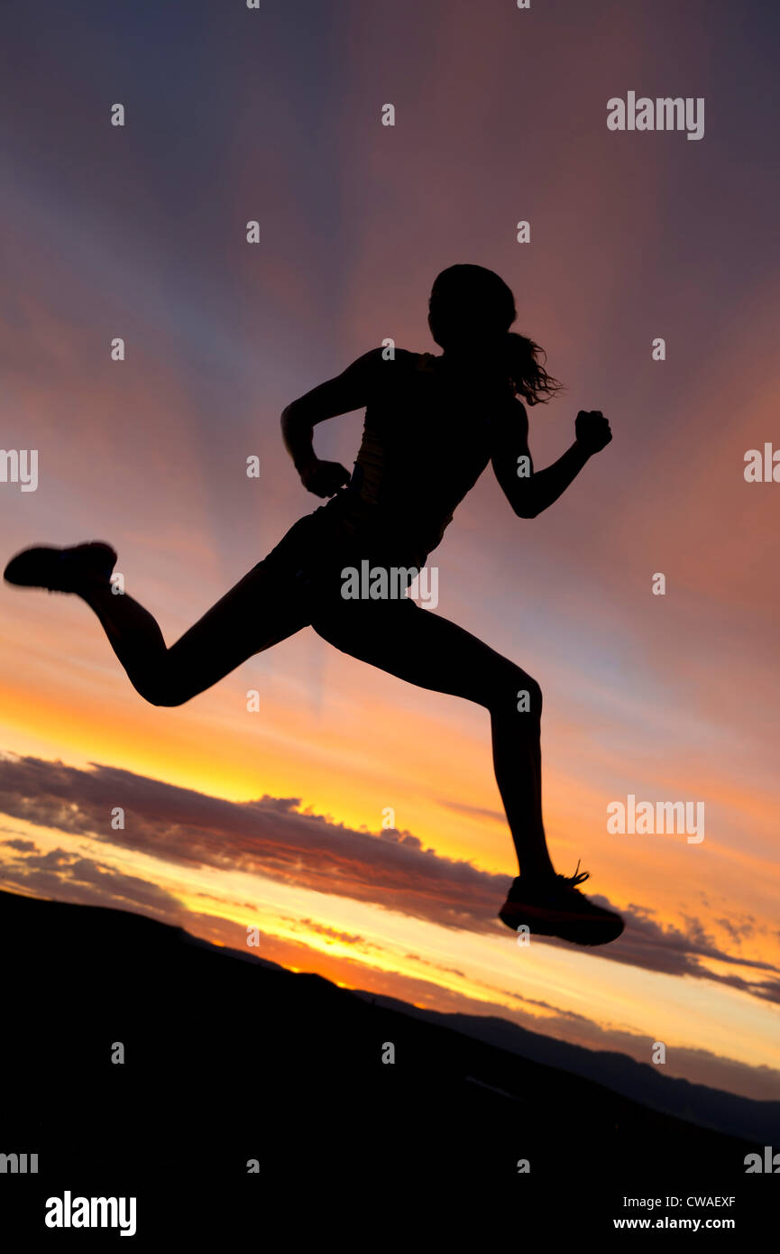 Silhouette d'athlète sautant contre coucher du soleil Banque D'Images