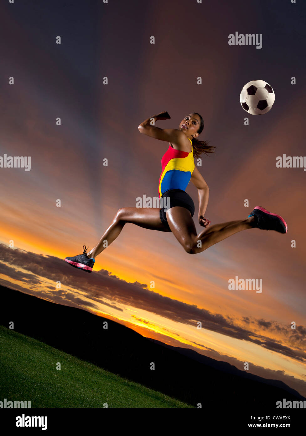 Football féminin au milieu de l'air contre le coucher du soleil Banque D'Images