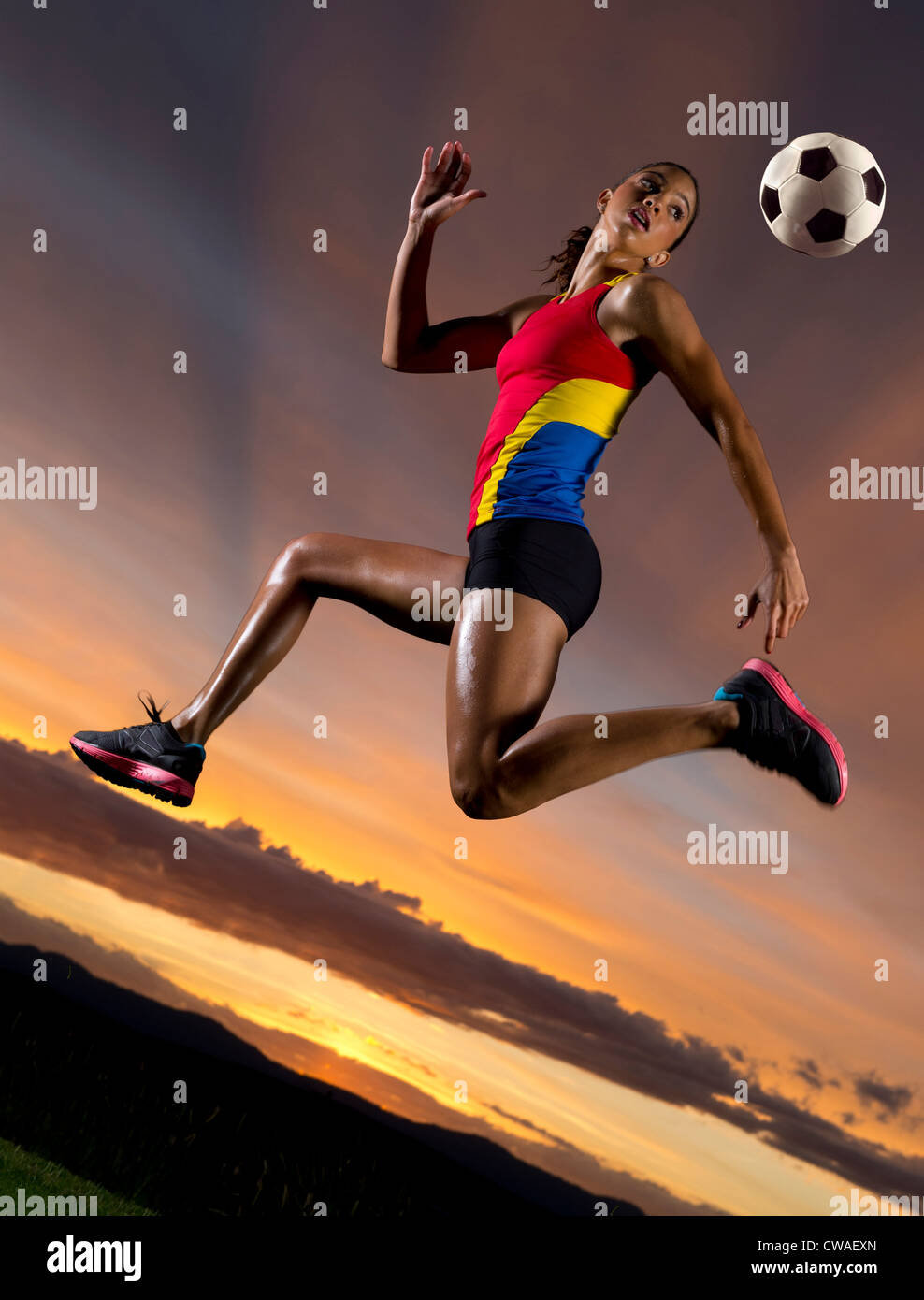 Football féminin au milieu de l'air contre le coucher du soleil Banque D'Images