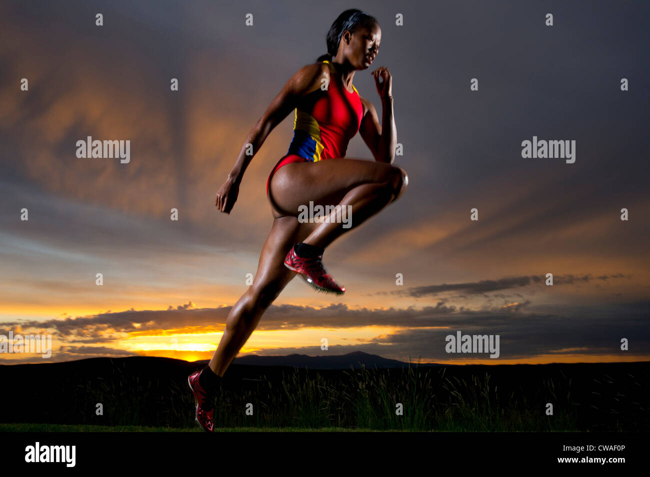 Sportif dans l'air contre le coucher du soleil Banque D'Images