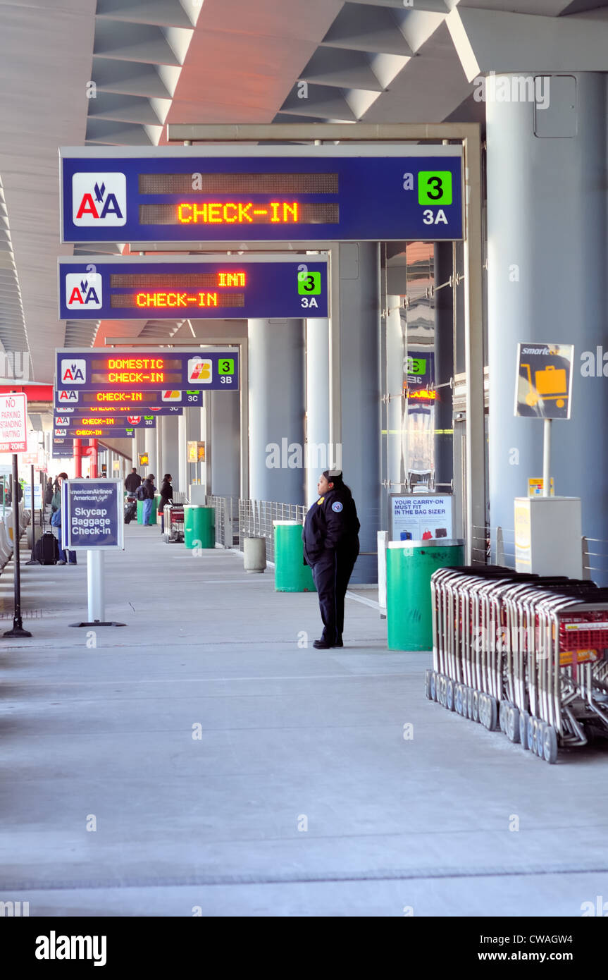 Gardien de sécurité se tient sous les panneaux guider les passagers terminaux de départ de Chicago O'Hare International Airport. Chicago, Illinois, USA. Banque D'Images