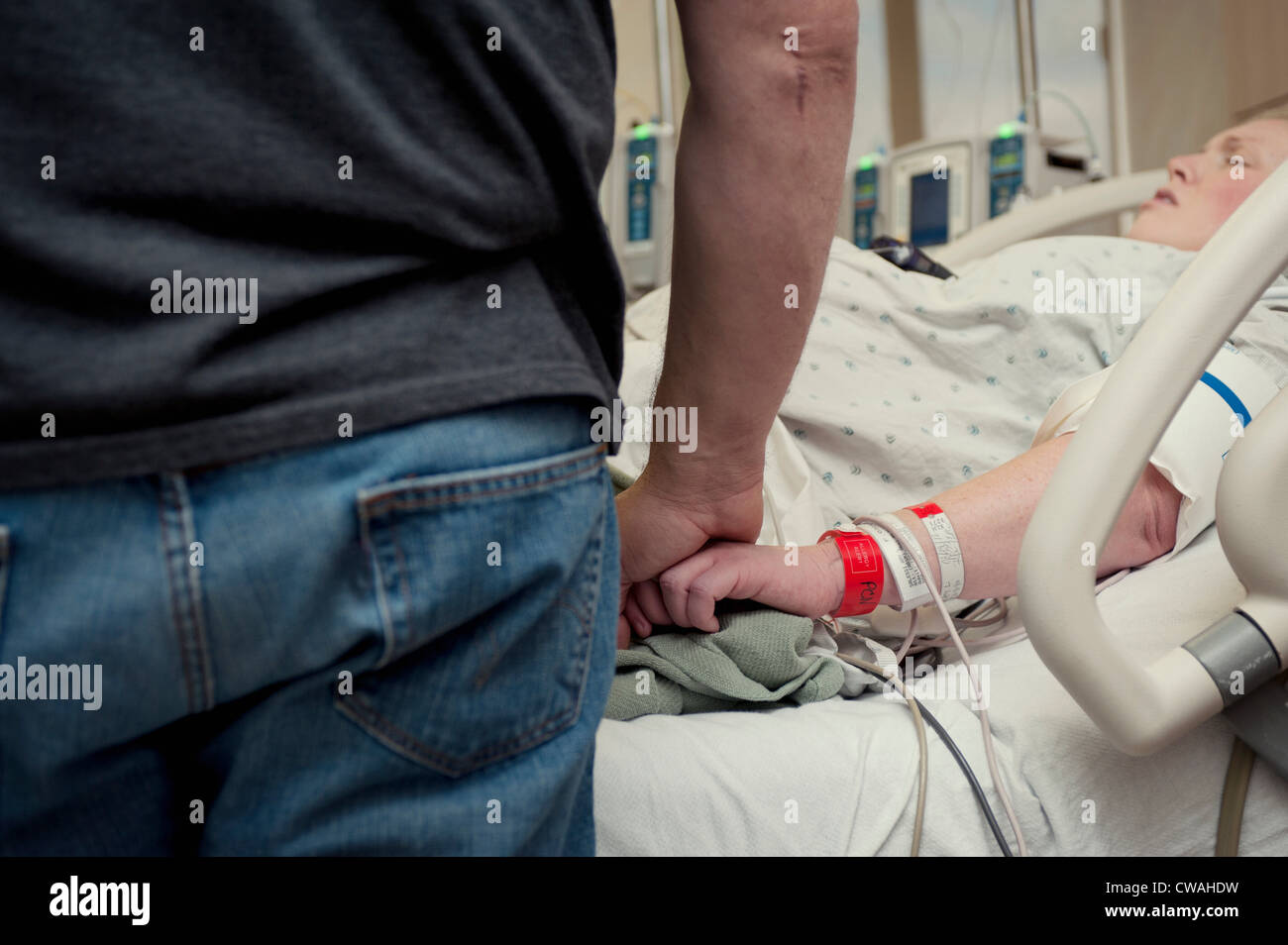 Man holding woman's hand in hospital room Banque D'Images