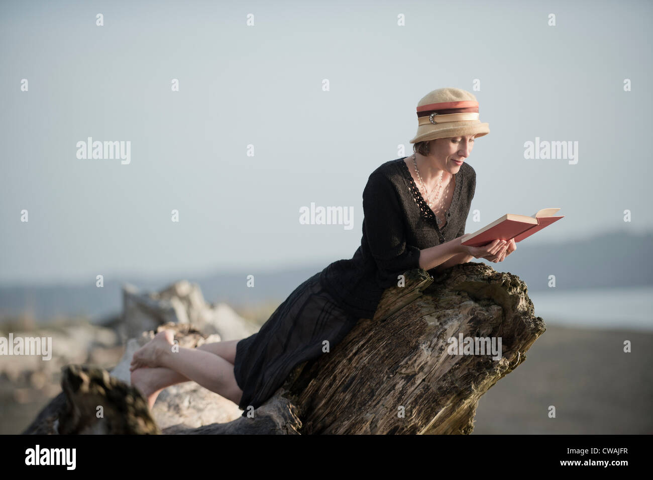 Femme couchée sur bois flotté, lire un livre Banque D'Images