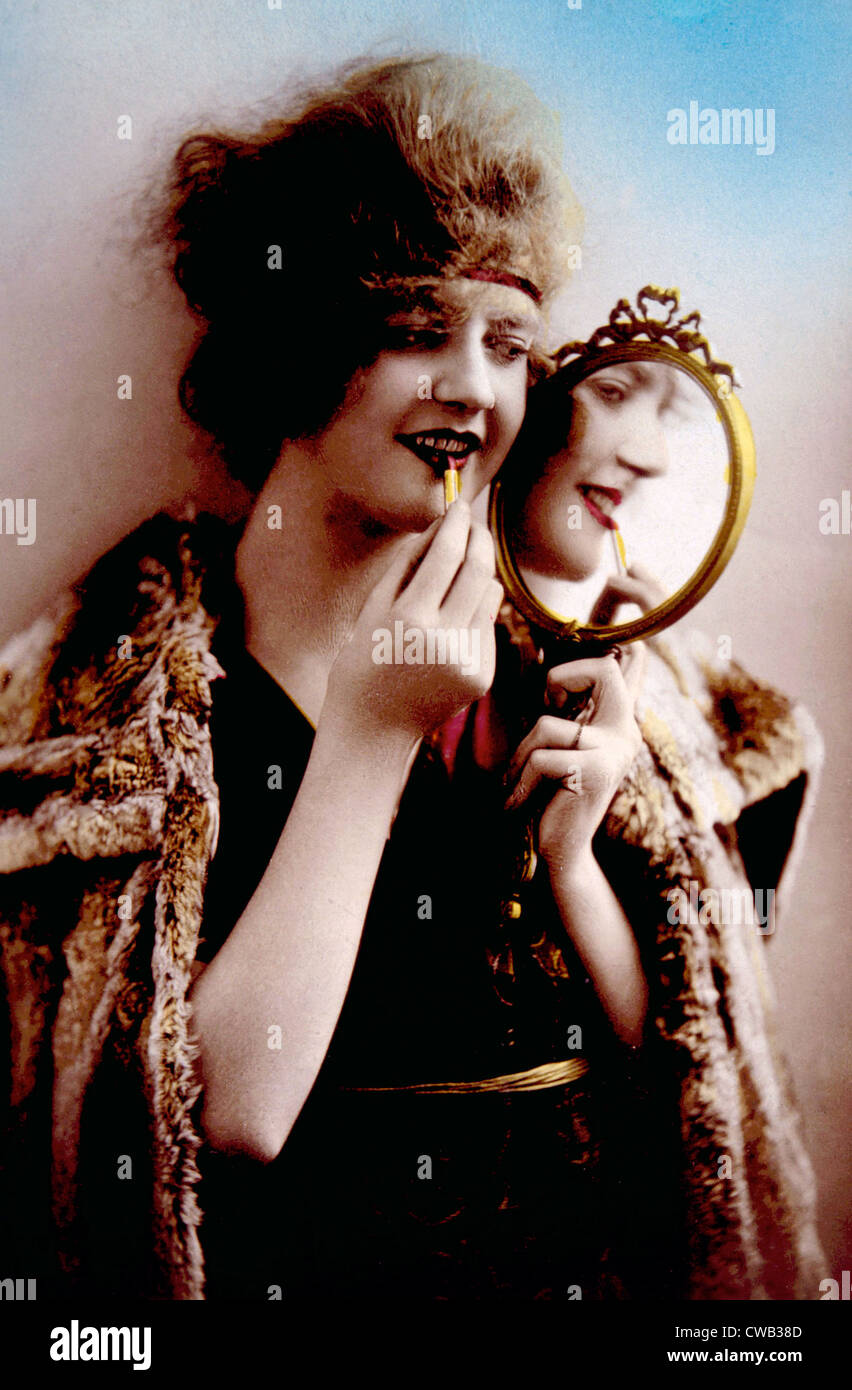 Femmes miroir tout en appliquant le rouge à lèvres, vers. 1900. Banque D'Images