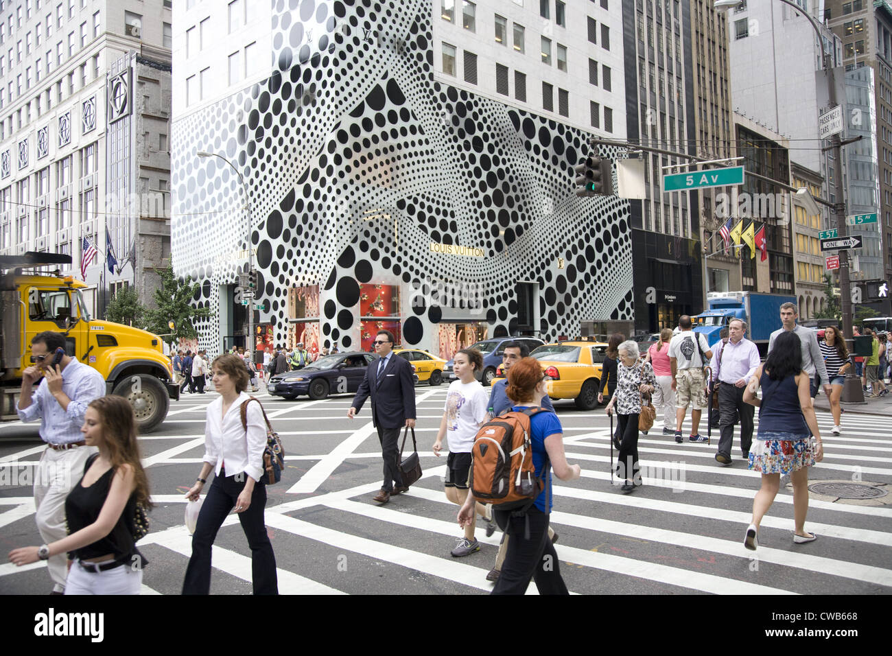 Les gens traversent la 5e Avenue à la 57e rue, avec l'arrêt de l'œil extérieur de la Louis Vuitton flagship store à l'arrière-plan. Banque D'Images