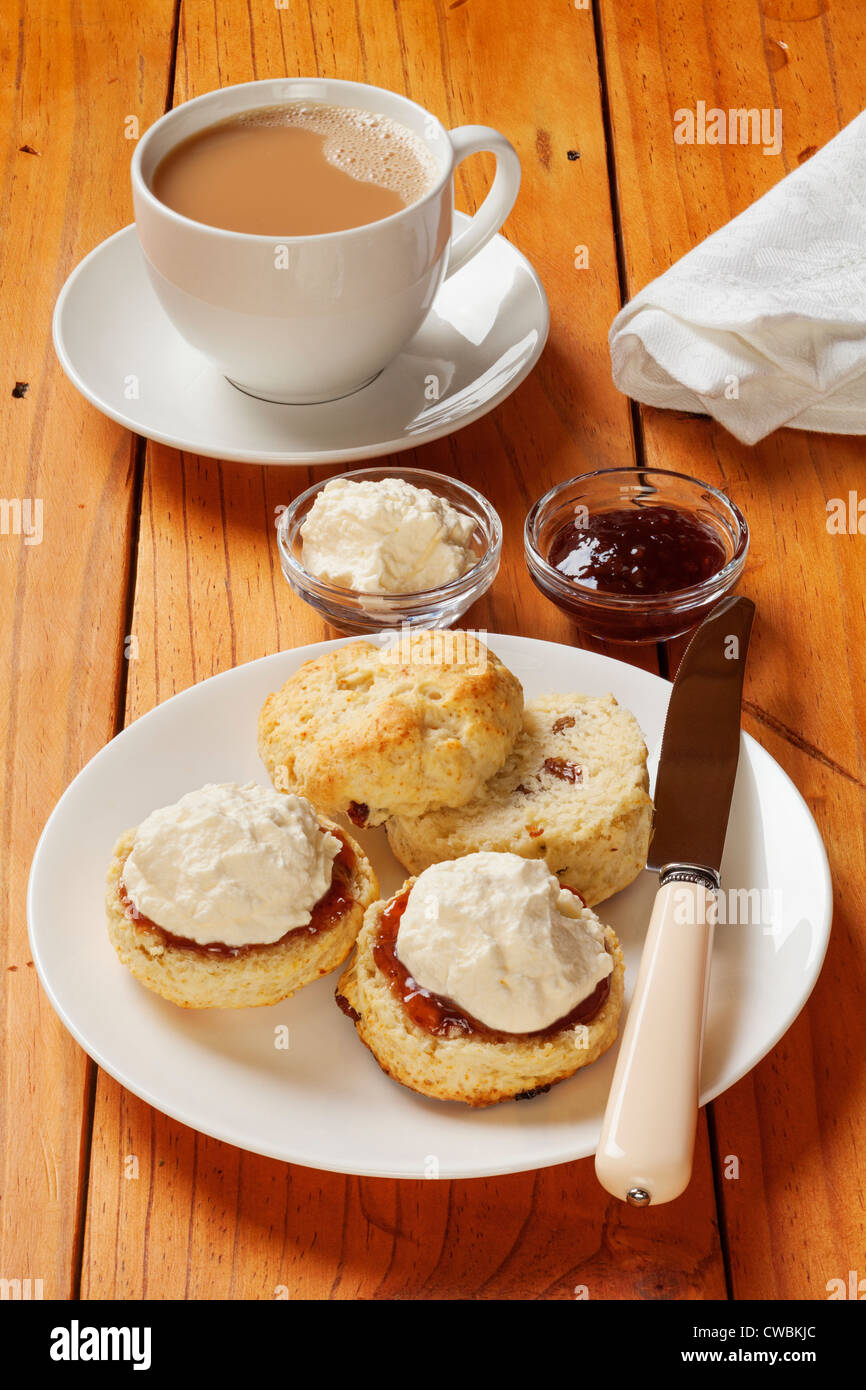 Thé crème Devon, scones, confiture, crème et une tasse de thé, sur une vieille table en pin. Banque D'Images