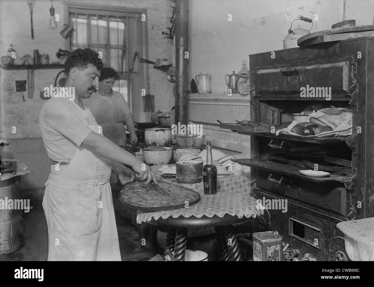 Immigrants pâtissier libano-syrienne de couper dans une pâte filo sweet réalisés dans la cuisine rustique de dans un New York City ethnic Banque D'Images