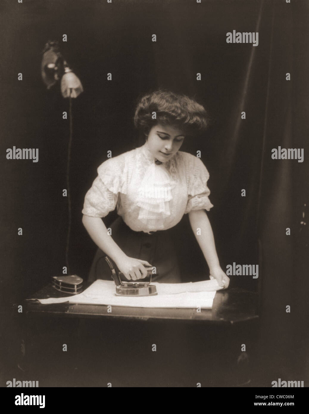 General Electric publicitaire photos d'une femme à l'aide d'un fer électrique branché sur la douille d'éclairage, ca. 1908. Banque D'Images