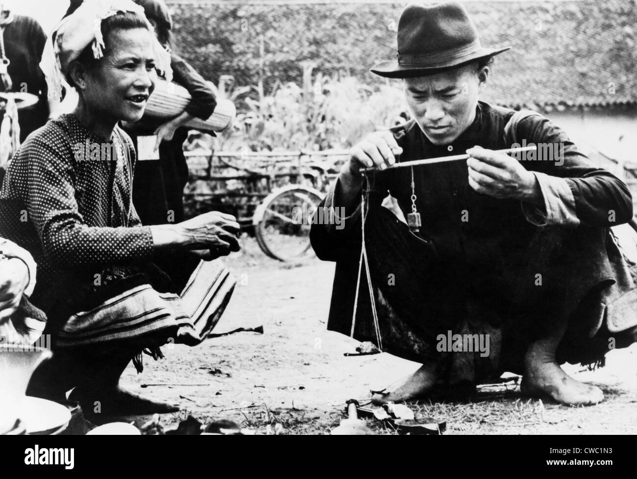 Vendeur de drogue pesant ouvertement l'opium pour un client dans un marché en plein air au Laos. 1954. Banque D'Images