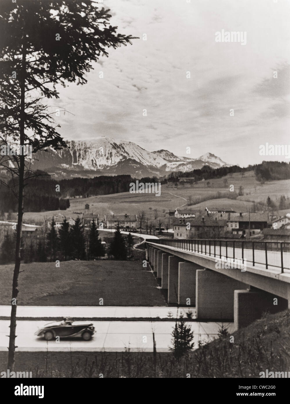 L'approche de l'automobile sur l'autoroute allemande de passage sur la campagne et les montagnes en arrière-plan. Ca. 1938. Banque D'Images