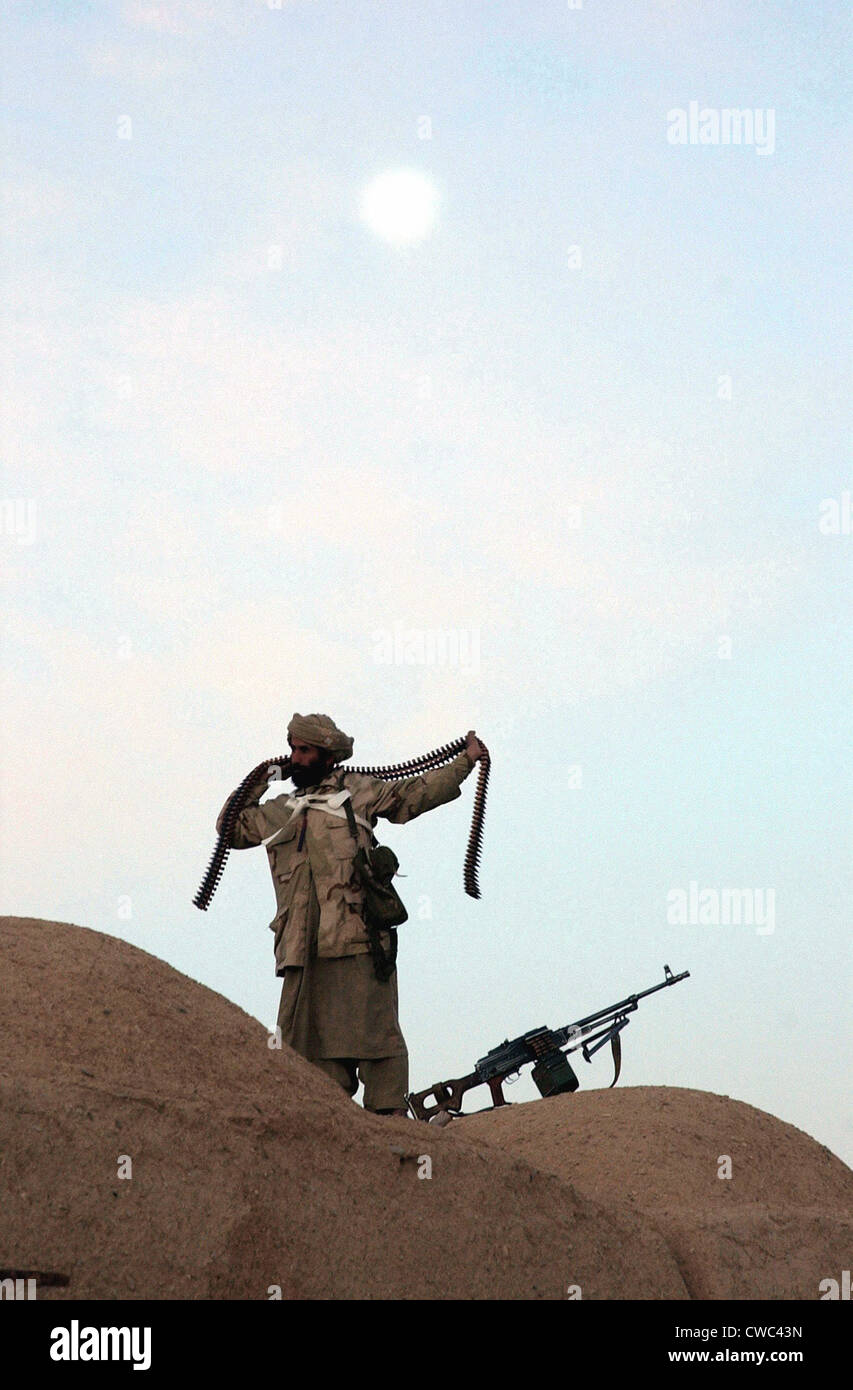 Un Anti-Taliban fighter encapsule une mitrailleuse Kalachnikov de bandoulière munitions autour de son corps. La province du Helmand, le 1er janvier 2002., Banque D'Images
