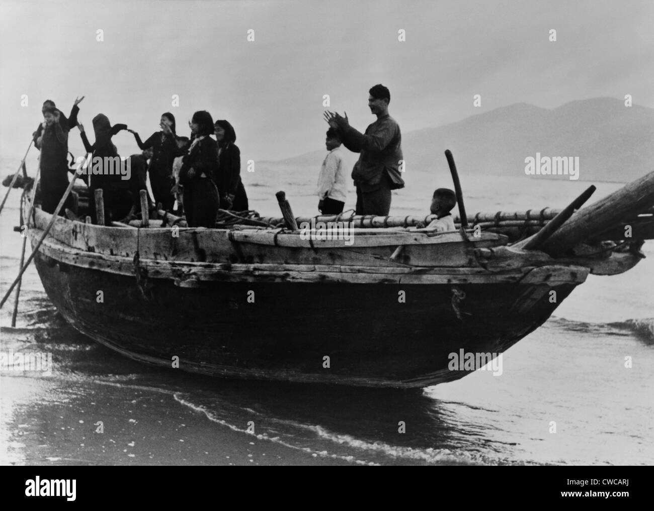 Réfugiés vietnamiens du Nord arrivent à Da nang, Vietnam du Sud. Debout dans un bateau de pêche, ils applaudissent car ils gagner bon port Banque D'Images