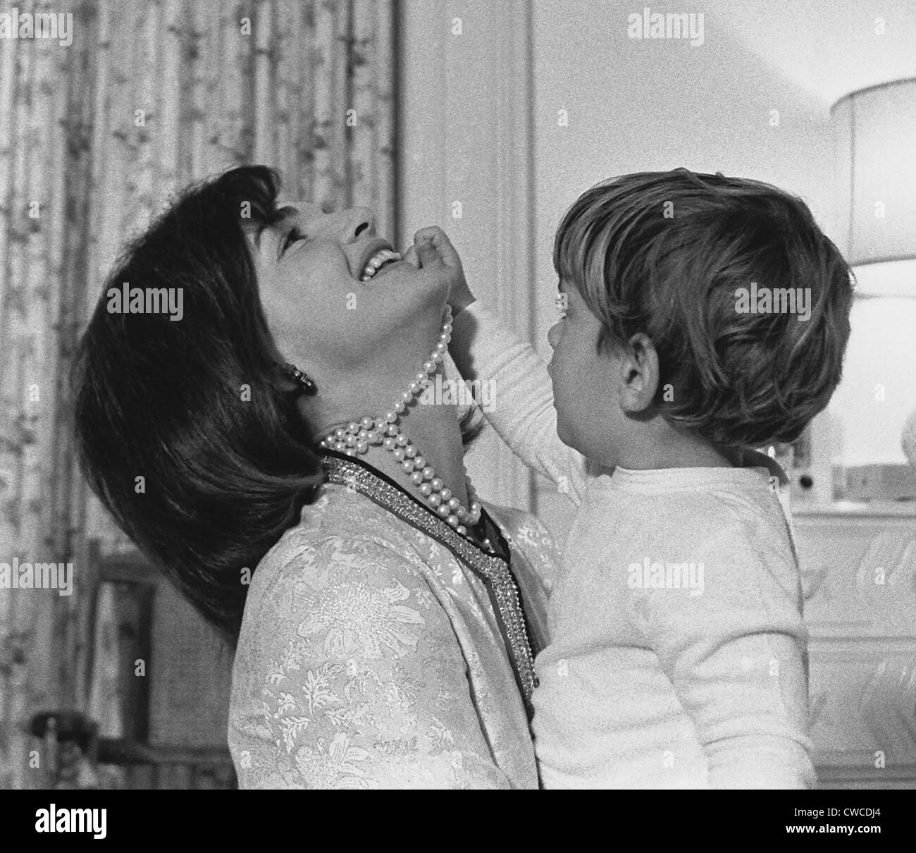 Première Dame Jacqueline Kennedy rit comme son fils John Kennedy Jr. joue avec son collier de perles-simulé à White House Banque D'Images