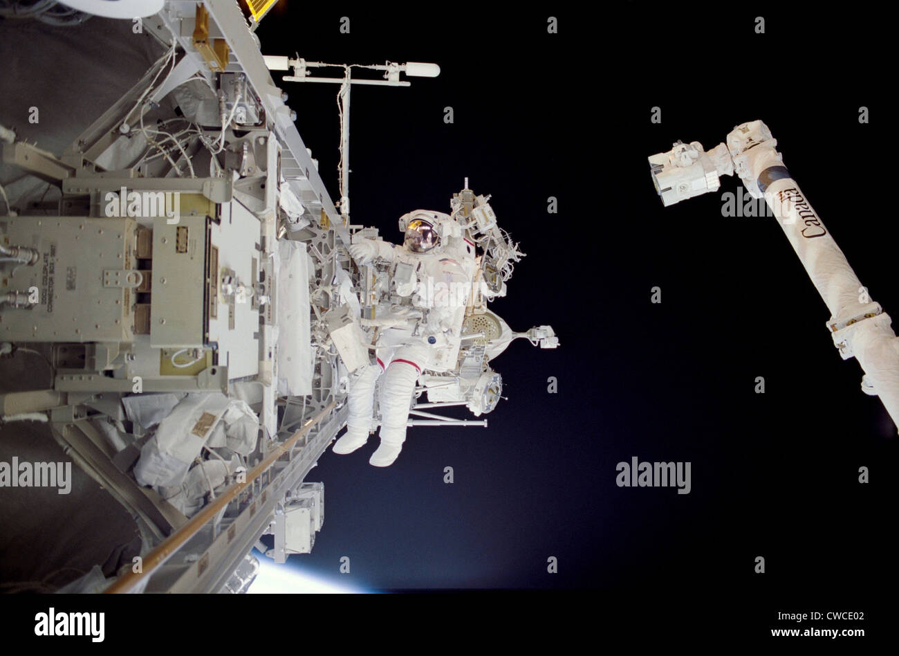 Les travaux de construction de la Station spatiale internationale. L'astronaute Michael Lopez-Alegria à marcher dans l'espace près du bras canadien tout en Banque D'Images