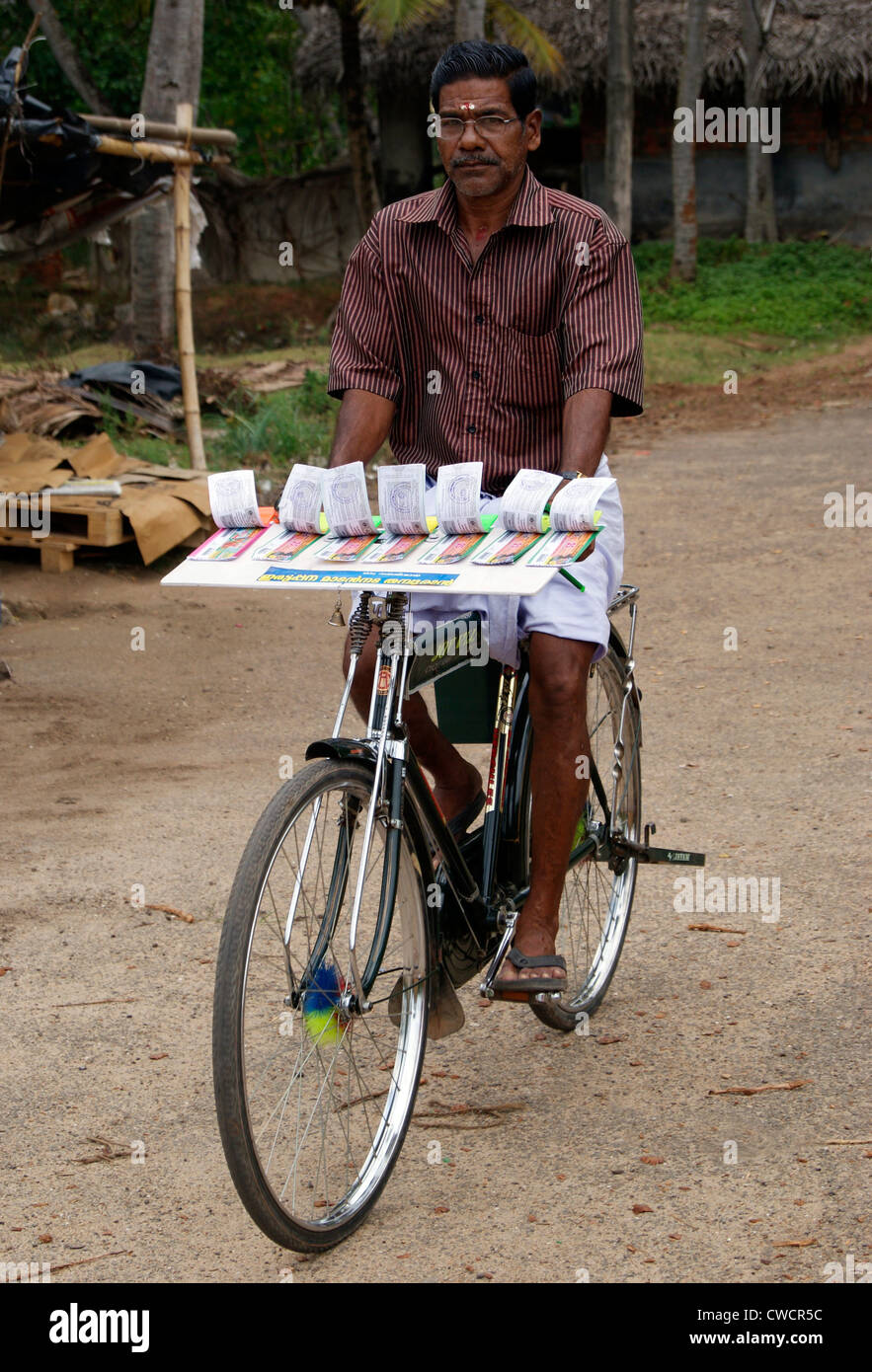 Vendeur de billets de loterie équitation location scène de Kerala, Inde.Le cycle homme utilisé pour vendre des billets de loterie en village autochtones Banque D'Images