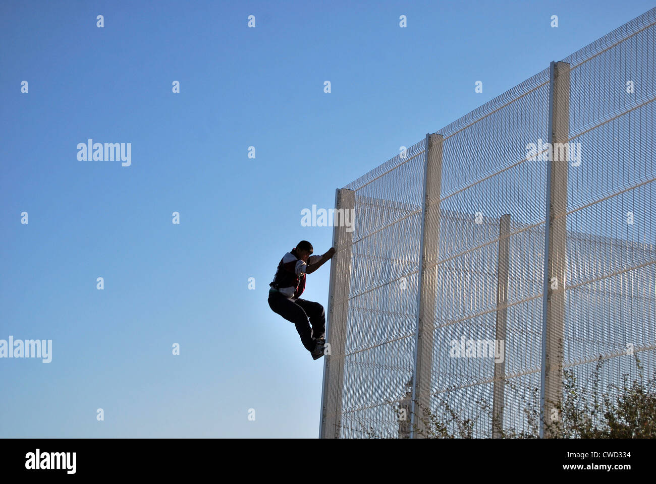 Un migrant à Calais monte une clôture de sécurité pour entrer dans le port de Calais et au Royaume-Uni. Banque D'Images