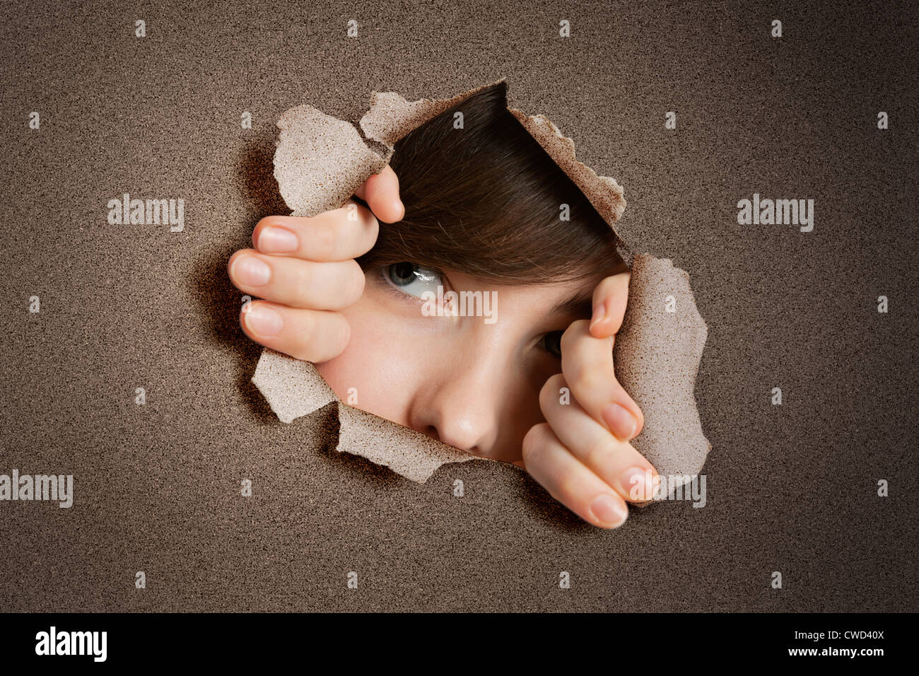 Les jeunes Middle Eastern woman peeking de papier déchiré trou blanc Banque D'Images