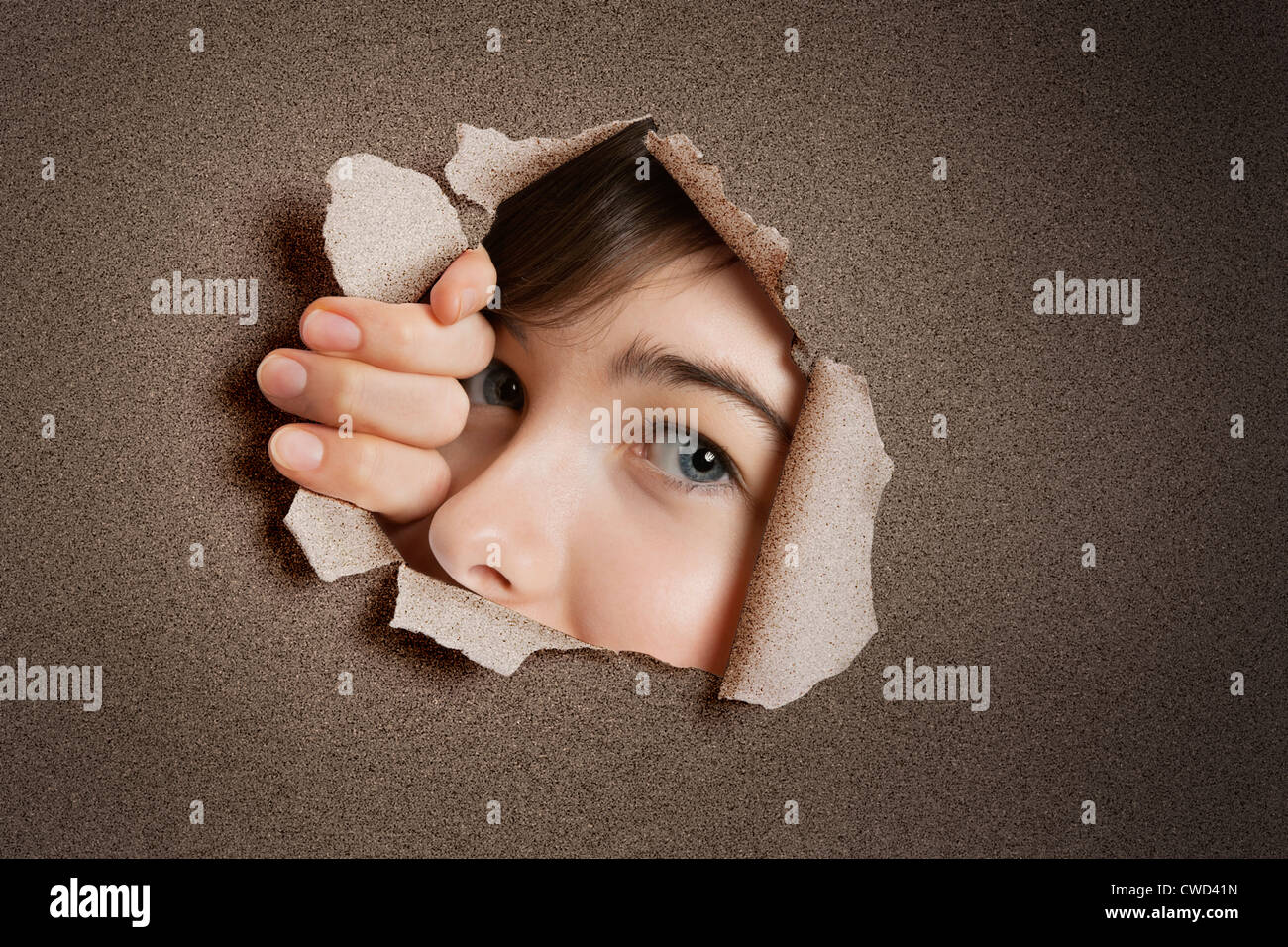 Portrait d'une jeune Middle Eastern woman peeking de papier blanc déchiré trou Banque D'Images