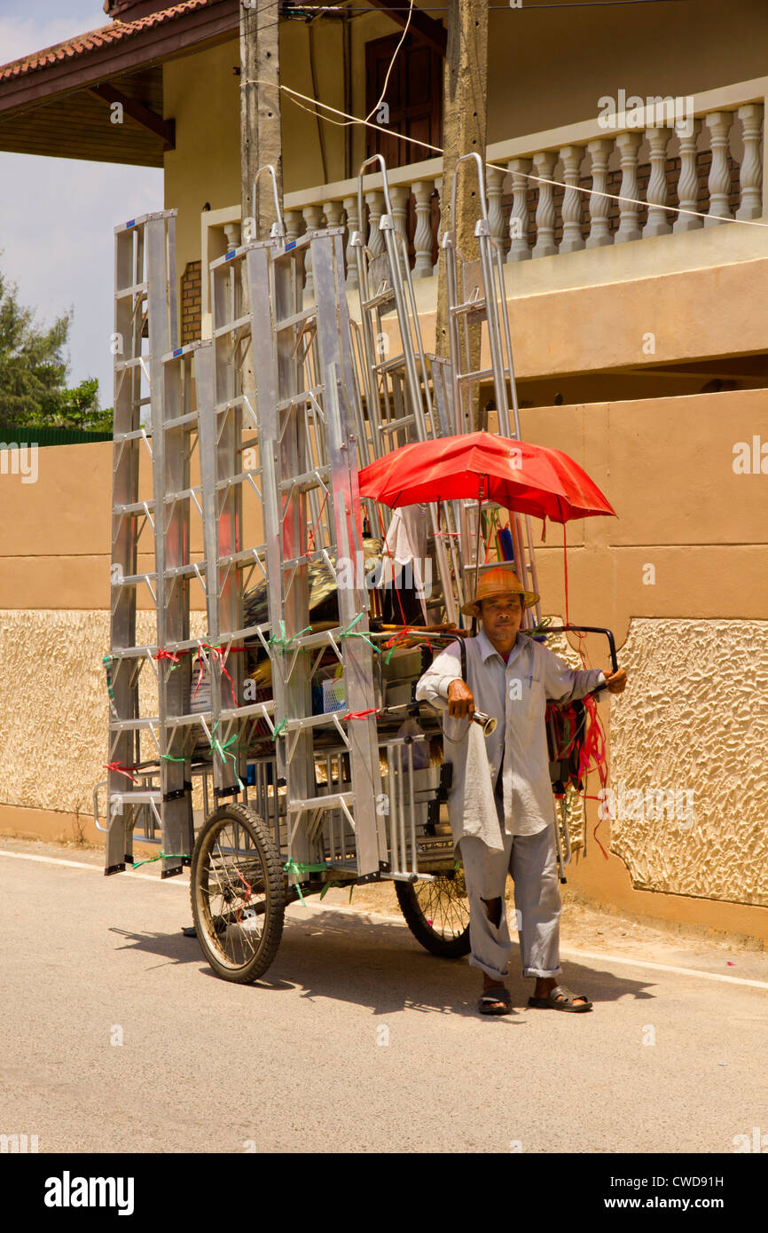 Un homme Thaï échelles en aluminium vente à partir d'un panier à deux roues. Banque D'Images