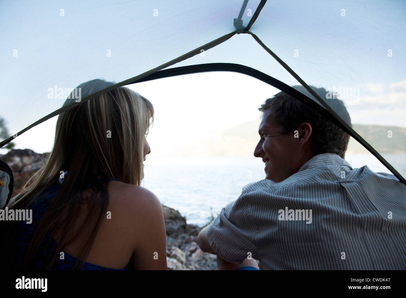 Deux jeunes adultes assis souriant dans une tente à côté d'un lac sur un voyage de camping dans l'Idaho. Banque D'Images