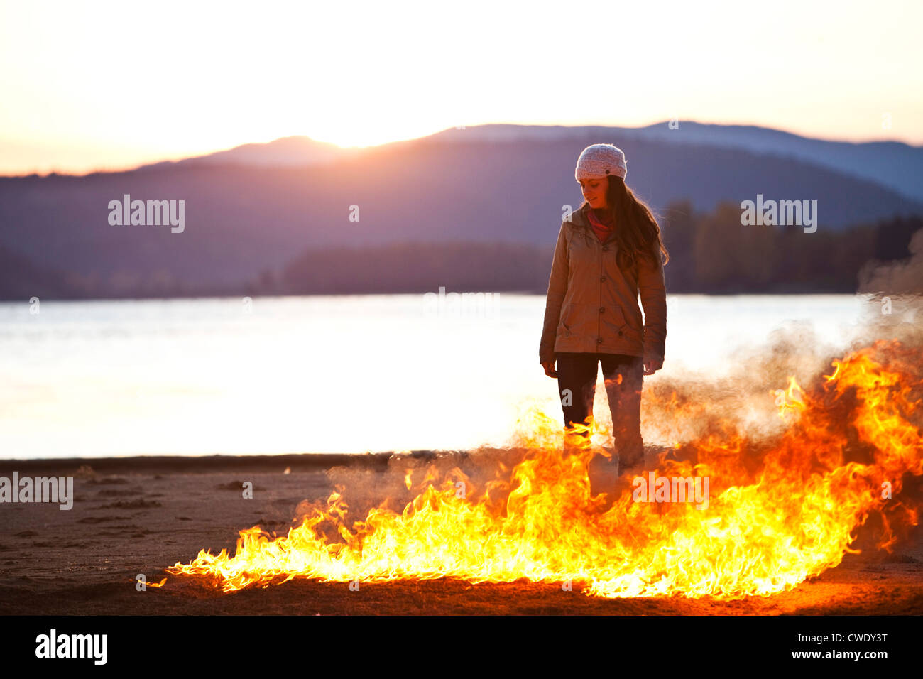 Une femme debout à côté d'un lac et de flammes qui fait rage dans l'Idaho. Banque D'Images