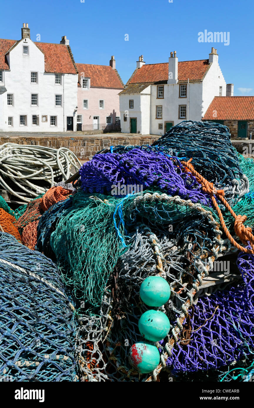 Pittenweem, East Neuk de Fife, Scotland, UK. Les filets de pêche empilés sur le quai avec des maisons d'un style typique de la région. Banque D'Images