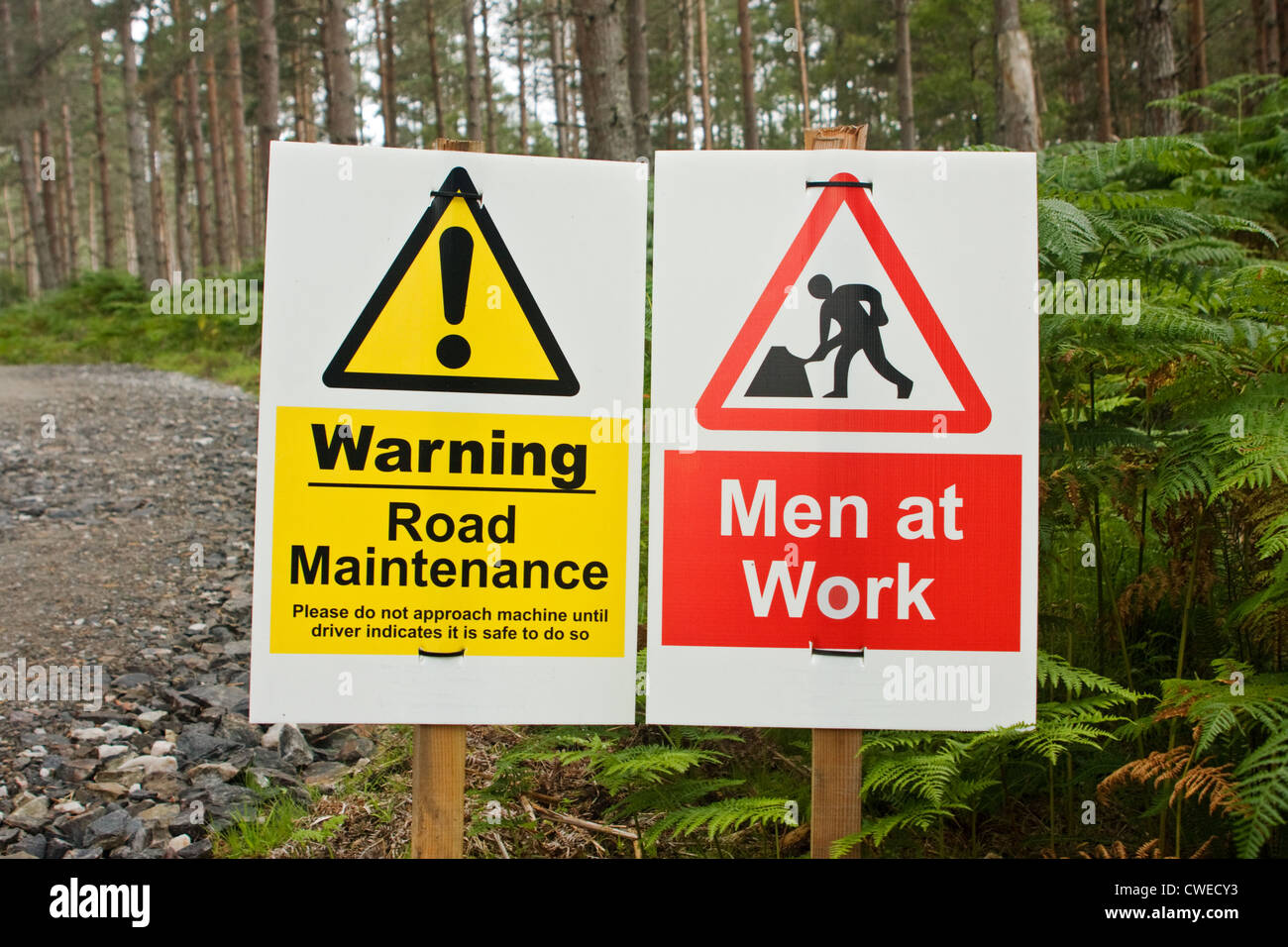 Un panneau d'avertissement sur un site dans une forêt avec le texte "hommes au travail" et "l'entretien des routes" Banque D'Images