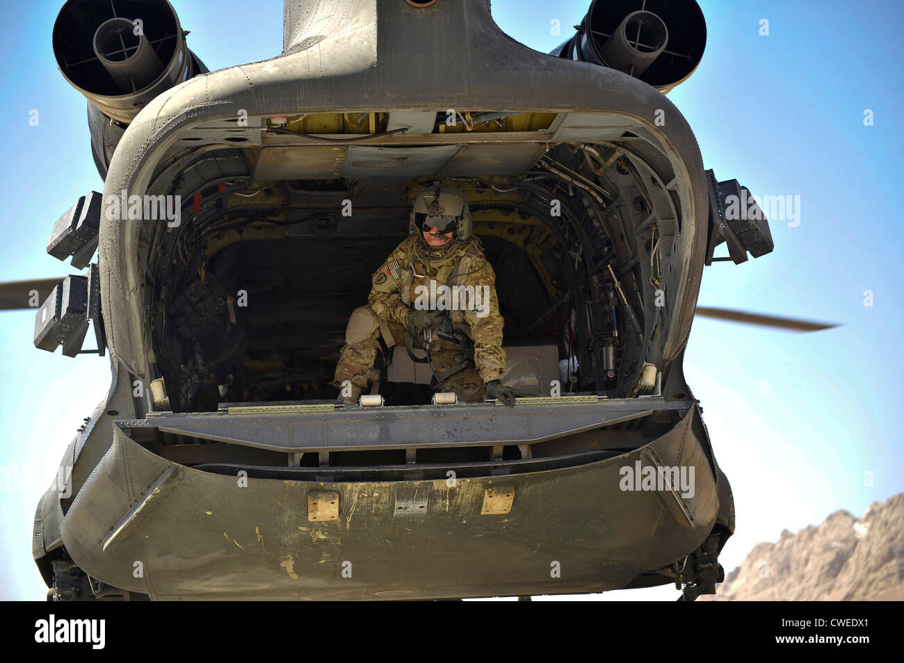 Un membre d'équipage à bord d'un hélicoptère CH-47 Chinook transmet les informations au pilote que l'avion s'approche d'une zone d'atterrissage à distance pour supprimer l'approvisionnement 10 mars 2012 dans le district de Shah Joy, province de Zabul, en Afghanistan. Fournir des hélicoptères des forces spéciales de la coalition un moyen efficace et fiable de transport du personnel et du fret dans les zones rurales de l'Afghanistan. Banque D'Images