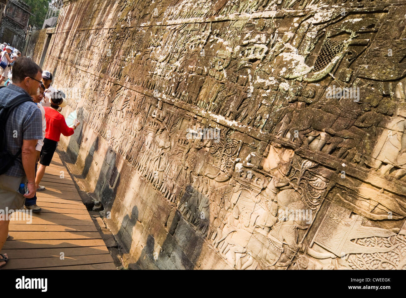 L'horizontale vue rapprochée de touristes à la recherche historique au bas-reliefs de la galerie extérieure du temple Bayon à Siem Reap Banque D'Images