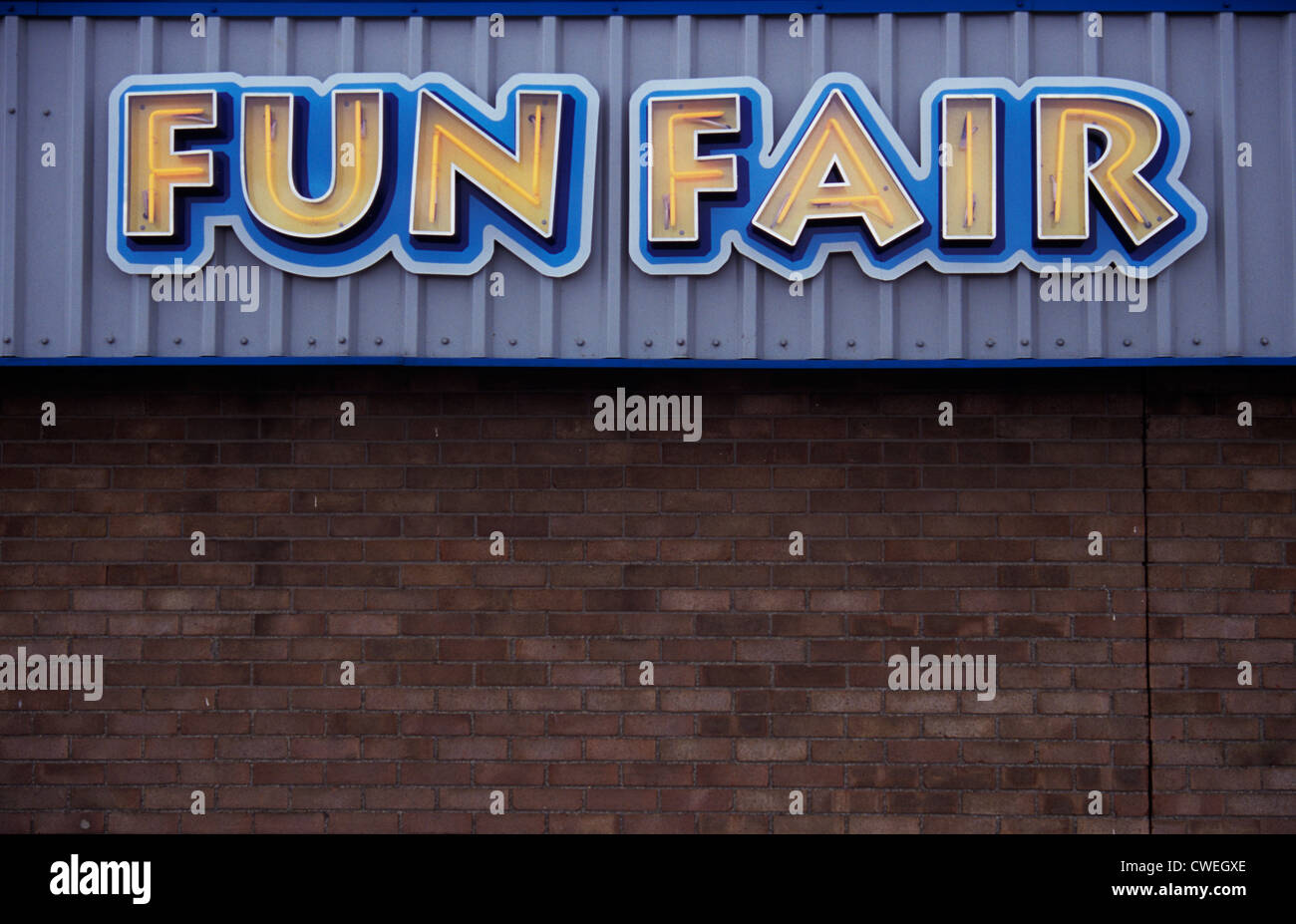 Lettres de néon jaune signe lumineux indiquant Fun Fair monté sur le fascia gris au-dessus de mur de brique ordinaire Banque D'Images