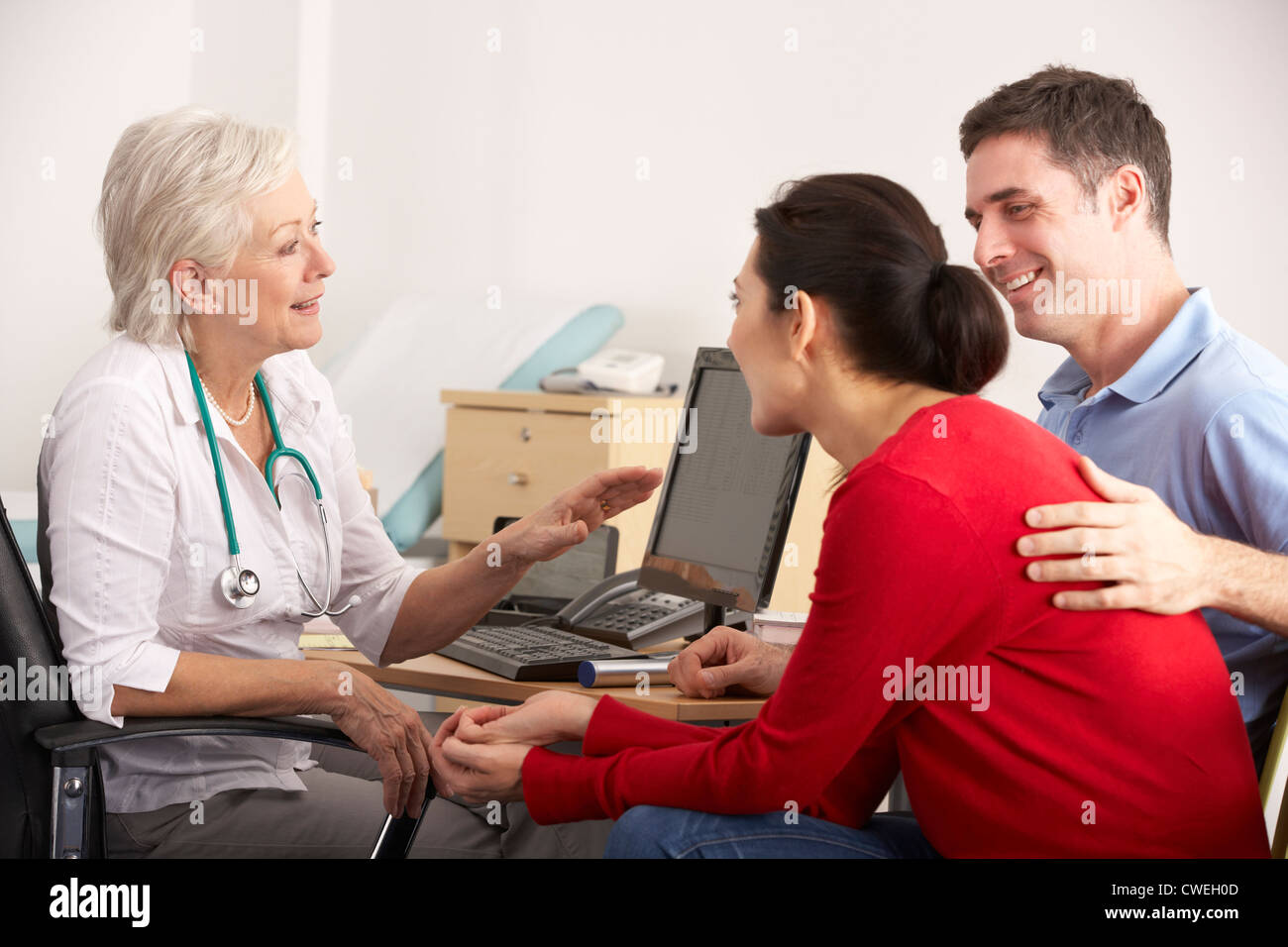 GP britannique parlant à couple heureux dans la chirurgie Banque D'Images