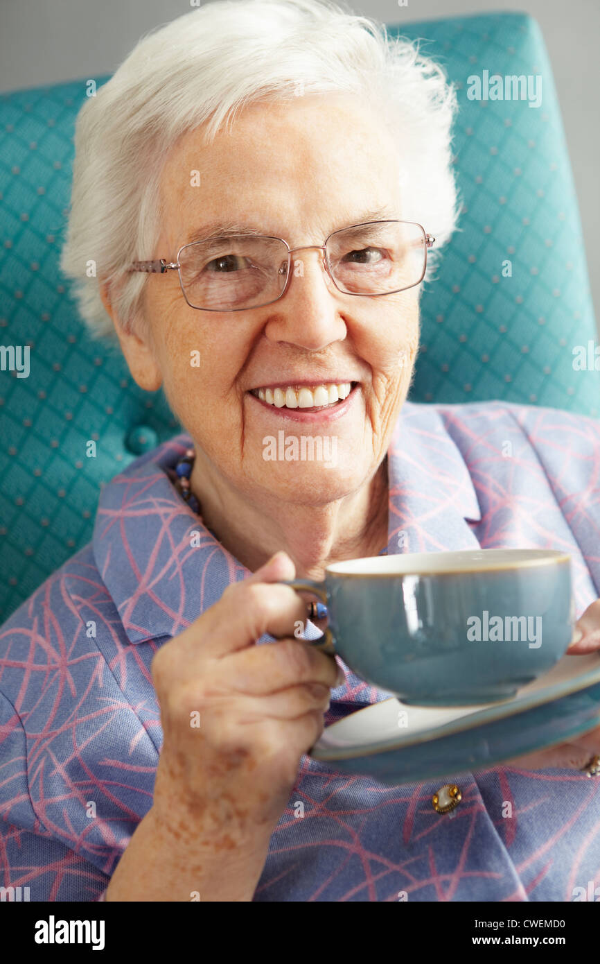 Senior Woman Relaxing in Chair avec boisson chaude Banque D'Images