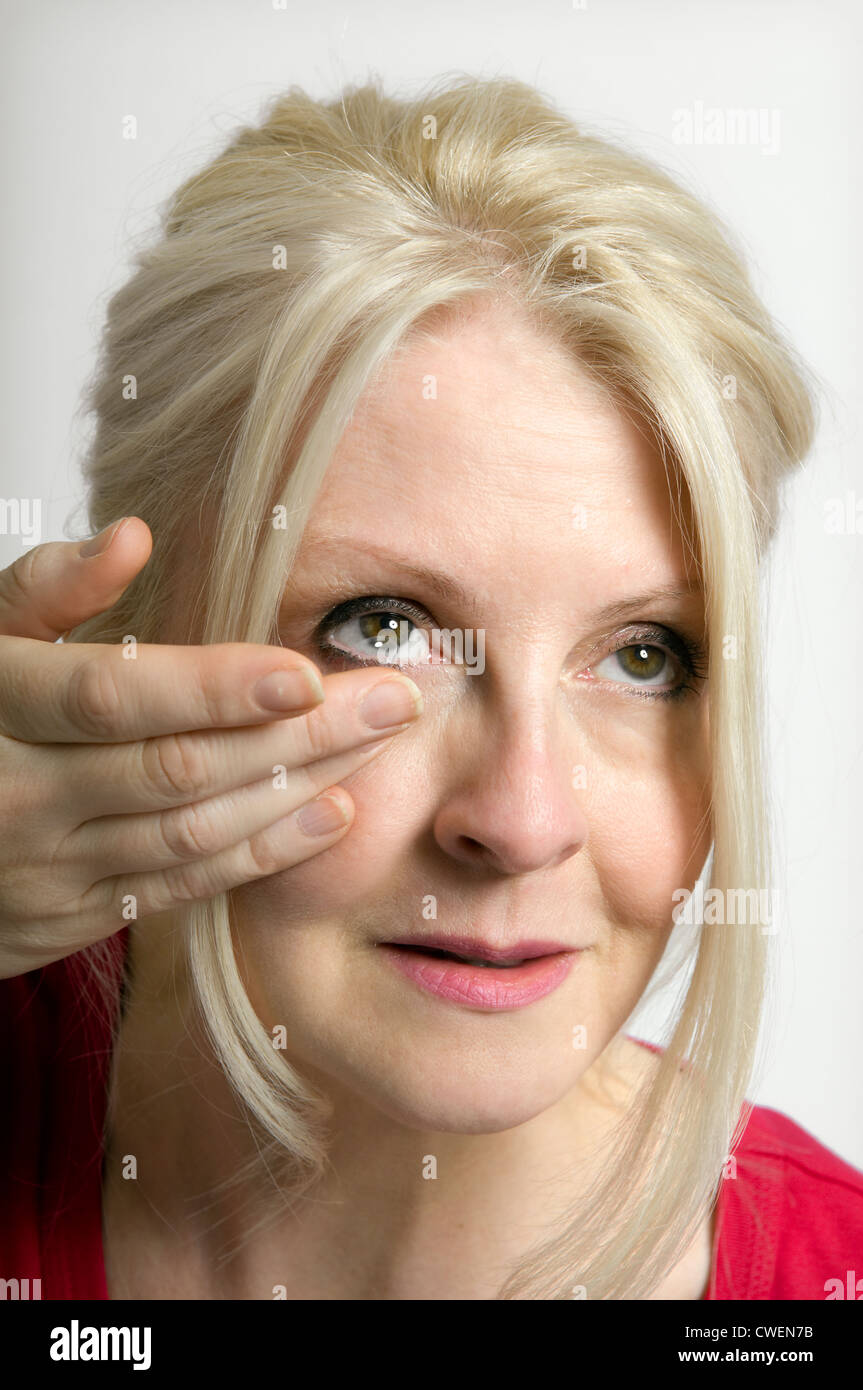 Femme aux cheveux blonds sur le point d'insérer la lentille de contact Banque D'Images