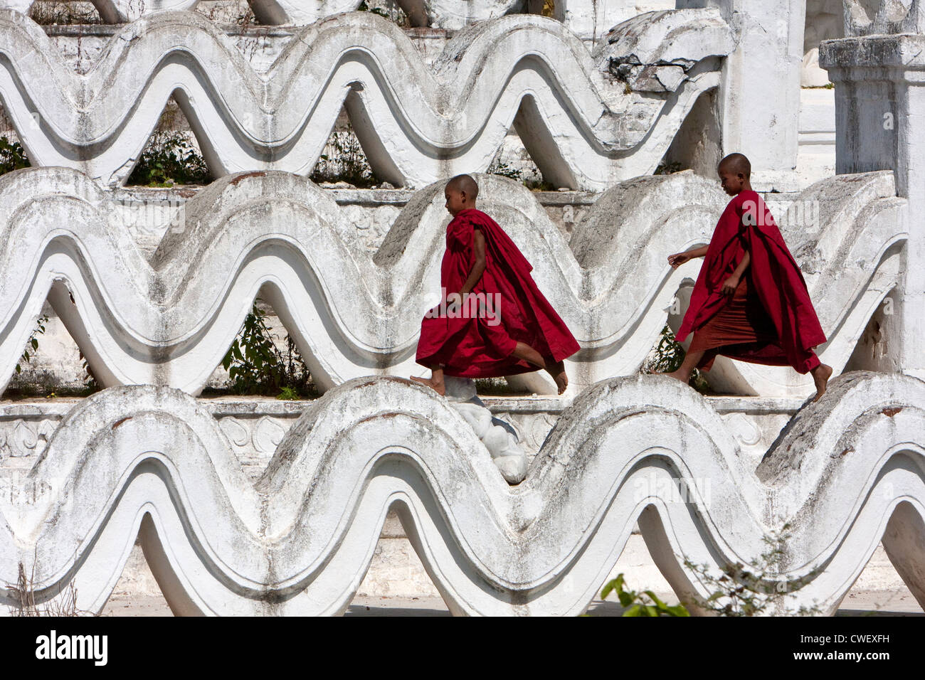 Le Myanmar, Birmanie. Mingun, près de Mandalay. Deux jeunes moines bouddhistes débutants marche sur l'Hsinbyume Paya, un stupa construit en 1816. Banque D'Images
