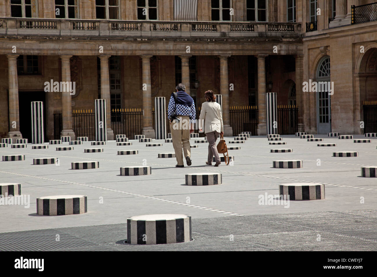 Deux personnes marcher dans le noir et blanc à rayures colonnes conçu par Daniel Buren au Palais Royal à Paris Banque D'Images