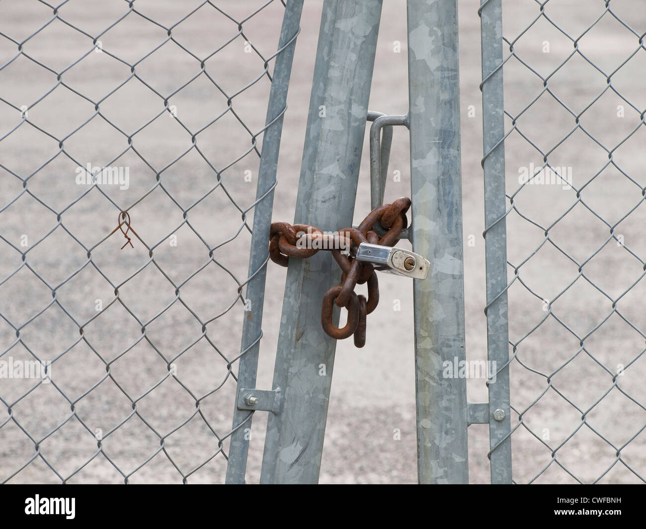 Cadenas avec chaîne rouillée fixant l'entrée de lot vide Banque D'Images