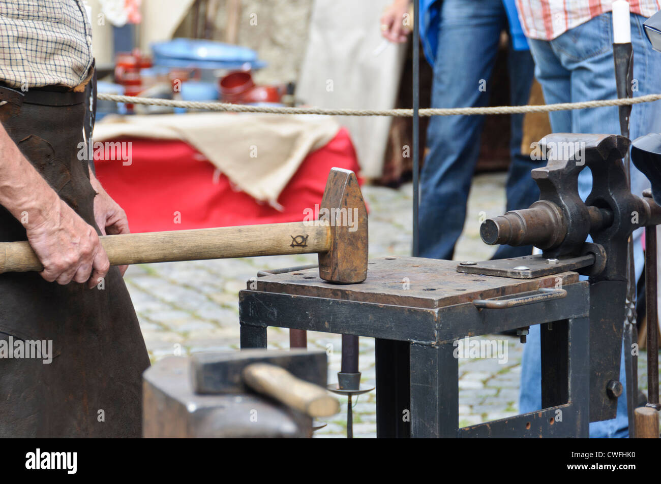 Artisan forgeron travaillant avec un gros marteau sur un établi avec un étau à un marché médiéval, Bad Wimpfen Zunftmarkt Banque D'Images