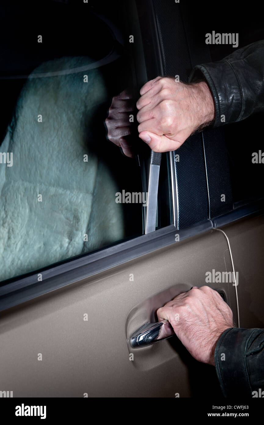 Un voleur de voiture utilise un Jim mince outil pour pop la serrure sur une porte de la voiture pour la voler. Banque D'Images