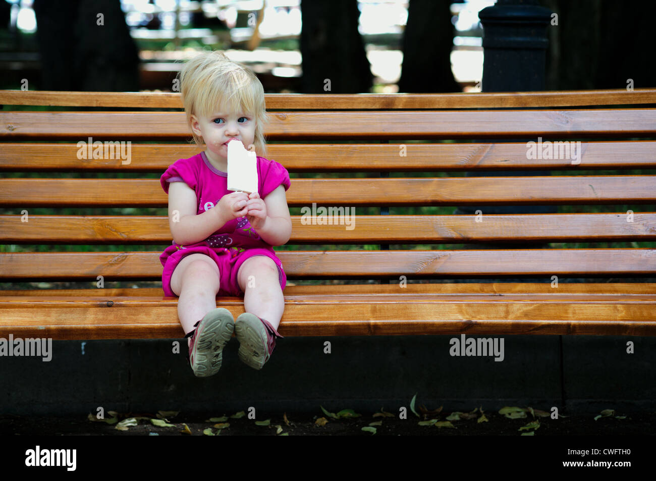 Un an baby girl eating ice cream au parc Banque D'Images