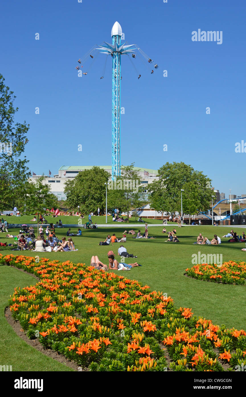 Les gens se détendre entre les parterres colorés dans la région de Jubilee Gardens avec Star Flyer président ride au-delà Banque D'Images