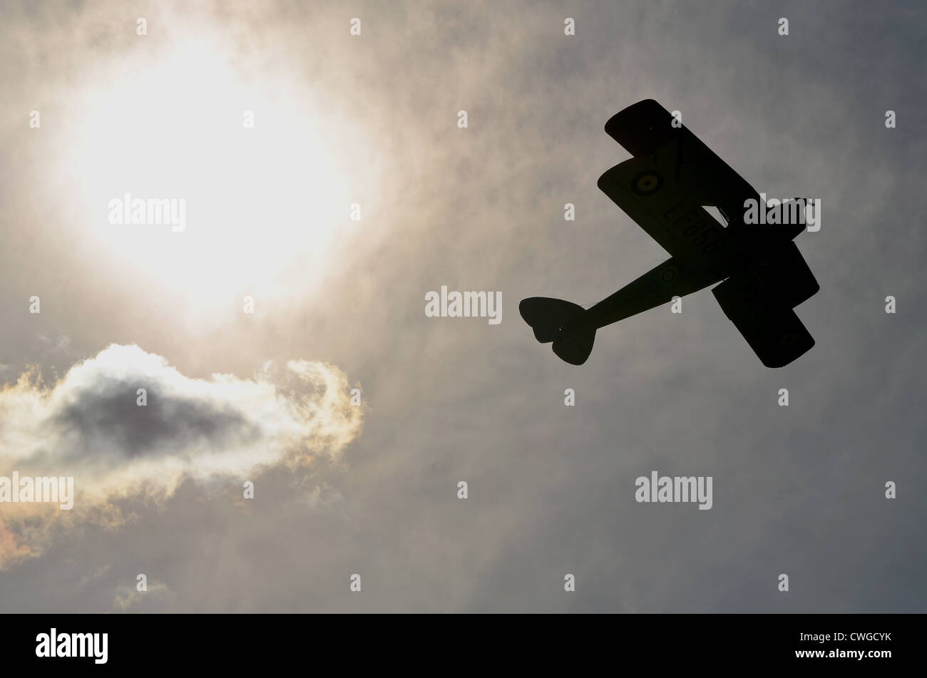 Silhouette d'un bi-plane voler à travers le ciel. Banque D'Images