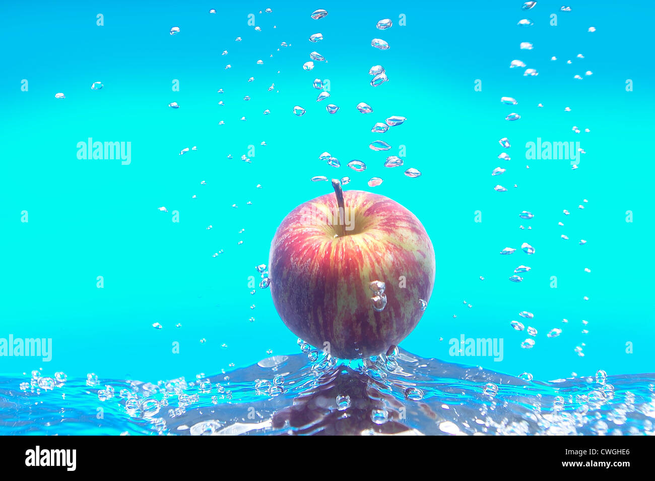 Pomme flottant dans de l'eau bleue avec des bulles flottant vers le haut Banque D'Images