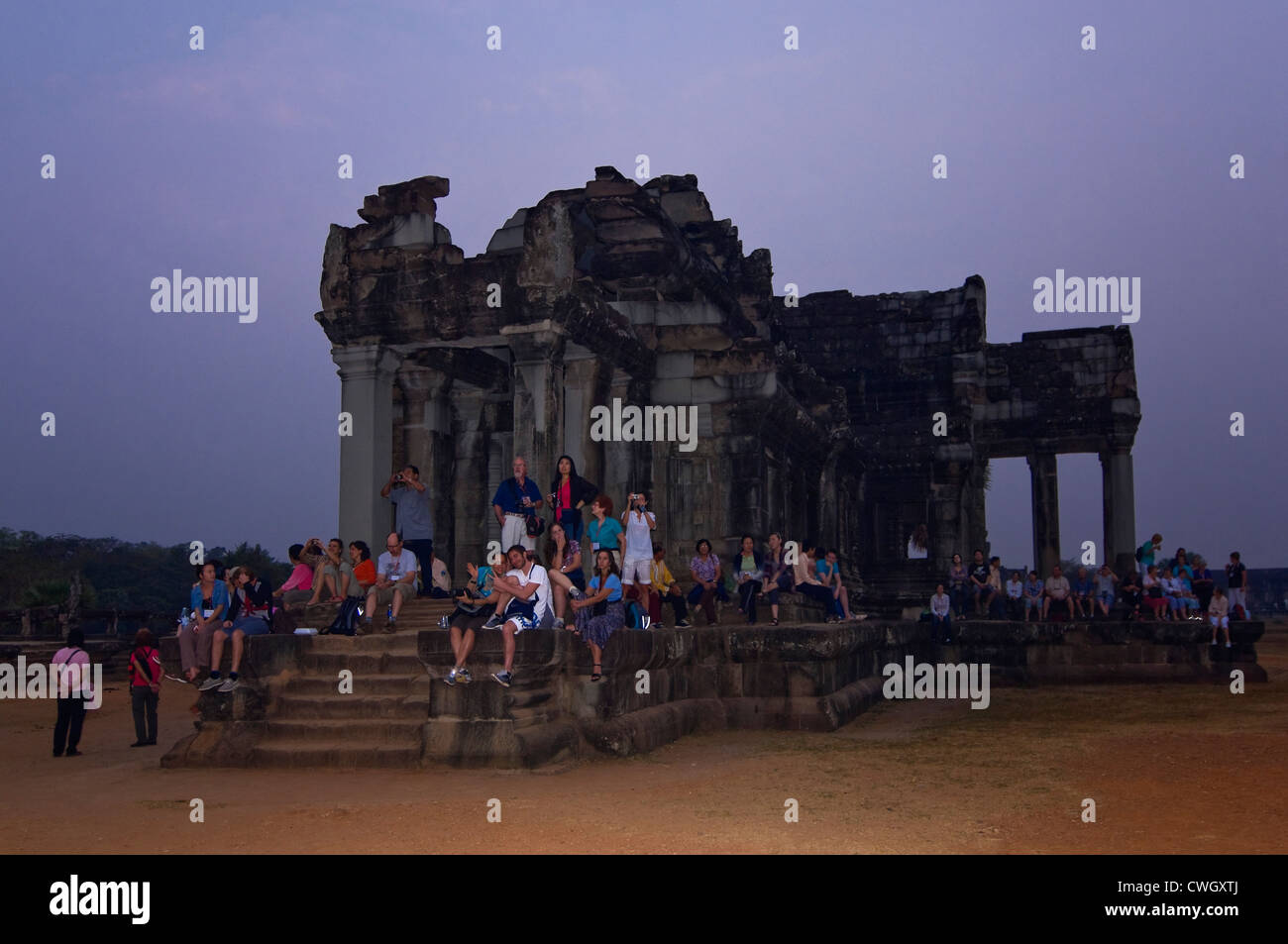 Vue horizontale de touristes rassemblés sur l'une des ruines pour regarder le lever du soleil se lever sur le Prasat Angkor Wat. Banque D'Images