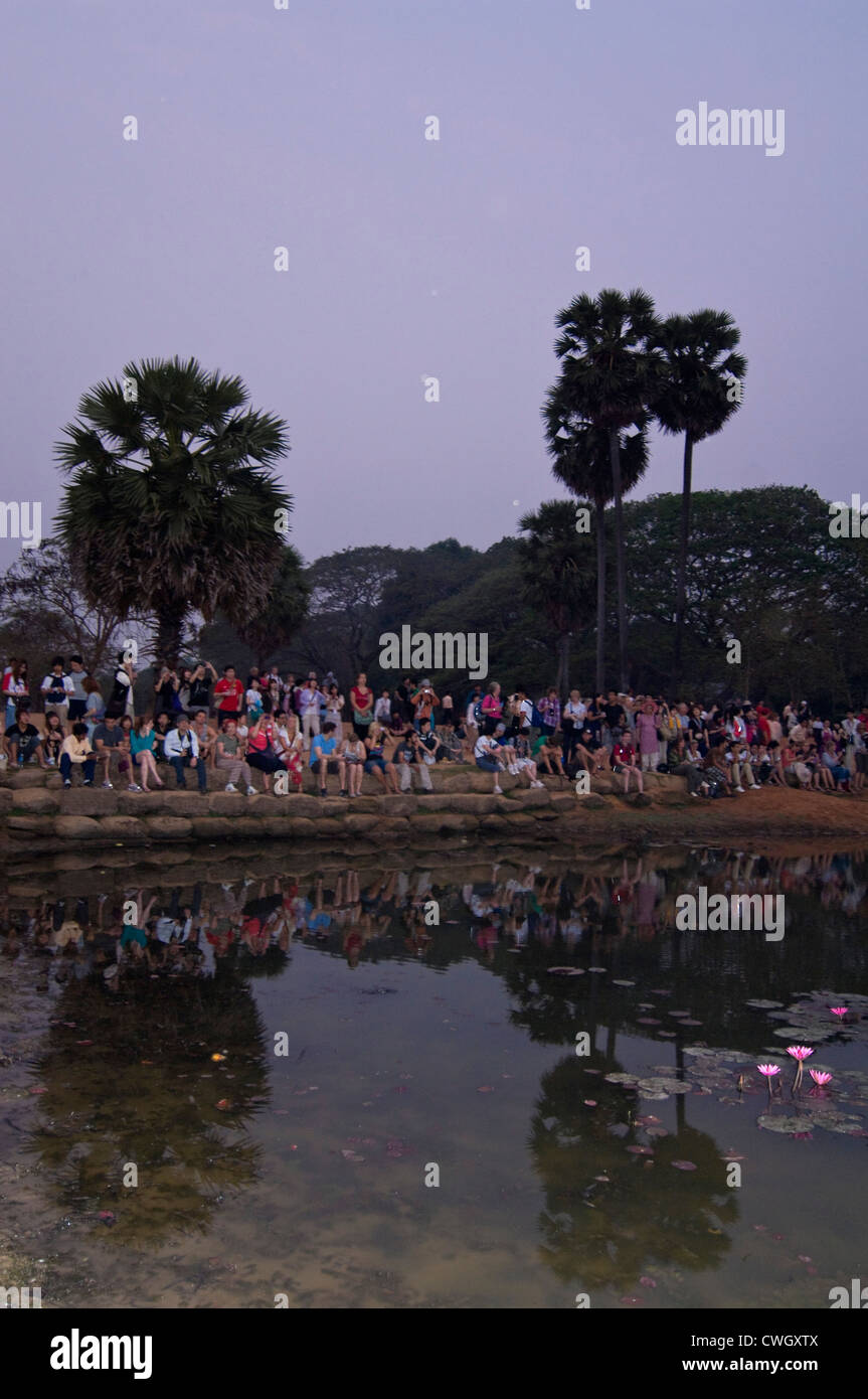 Vue verticale de touristes assis ensemble autour d'un lac à regarder le lever du soleil sur Angkor Wat Prasat. Banque D'Images