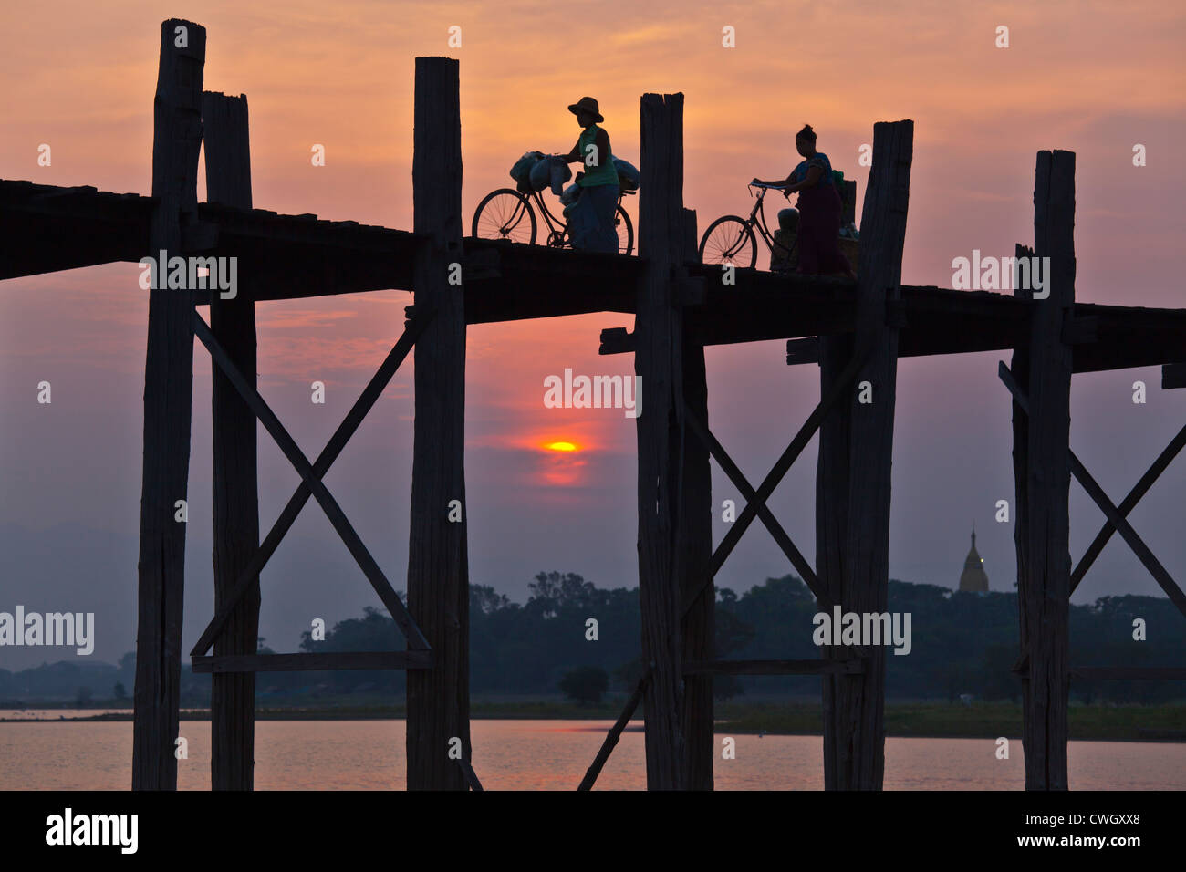 Les Birmans utilisent le pont en teck U BEINS de commuer à travers le lac Taungthaman au lever du soleil - AMARAPURA, MYANMAR Banque D'Images